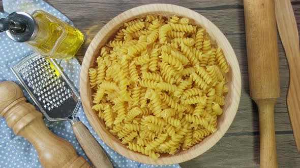 Fusilli Pasta Dry on the Table Slowly Rotates. On Wooden Background. Top View. alt
