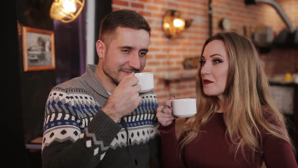 Beautiful Couple at the Bar in a Cafe Drinking Coffee and Talking
