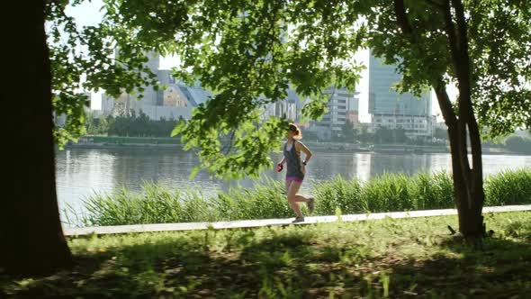 Female Athlete Running along Embankment alt