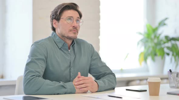 Middle Aged Man Sitting in Office Thinking  alt