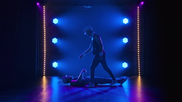 Group of Male Gymnasts Perform Acrobatic Stunts on Balancing. Silhouettes of Two Men on a Black alt