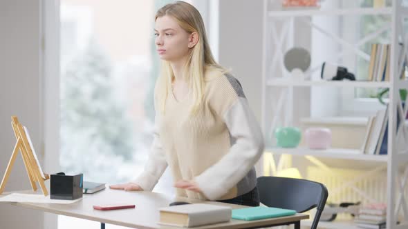 Young Blind Caucasian Woman Standing Up From Table and Walking to Door at Home alt