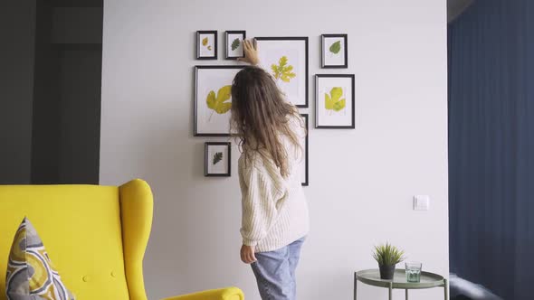 Curly Haired Brunette Approaches Leaves Composition on Wall