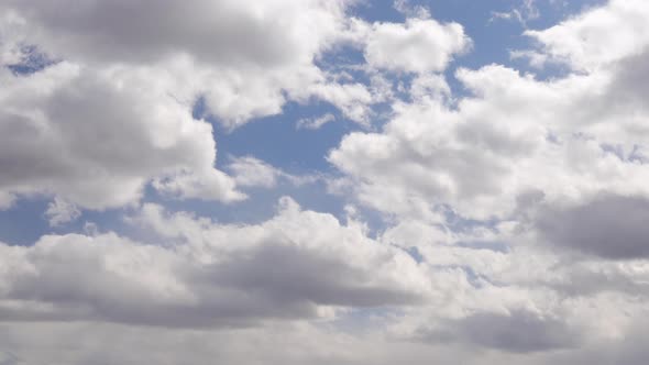 Fast paced view of clouds rolling around in the blue sky. Cotton ball looking clouds. Blue sky.