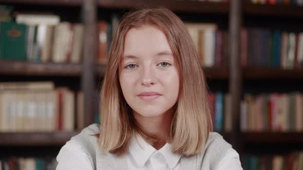 Close Up Portrait of Young Pretty School Girl Years 1214 Smiling Happy Looking at Camera in Library alt