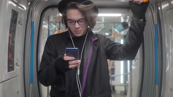 Young handsome stylish man wearing black hat and eyeglasses with headphones listening to music, alt