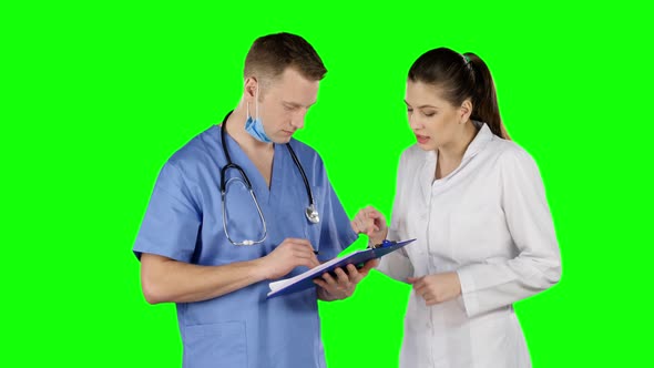 Two Doctors Talking with Clipboard. Green Screen alt