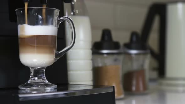 Cappuccino From the Coffee Machine Is Poured Into a Glass Cup