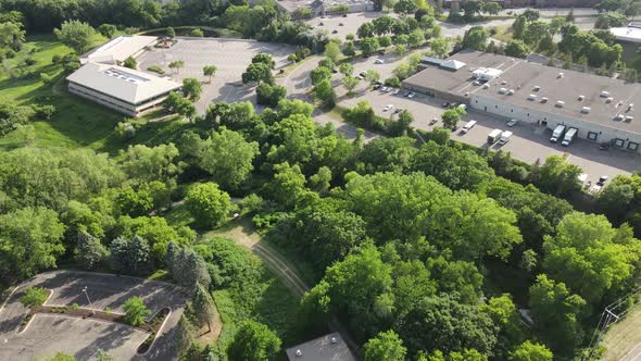 Drone view over industrial business area at the edge of Excelsior, Minneota. Lush foliage around.