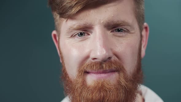 A Red Bearded Doctor in a White Gown is Looking at the Camera and Smiling