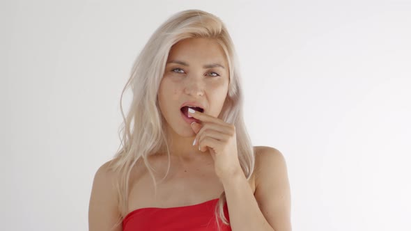 Young Blonde Woman Putting Chewing Gum in Mouth alt