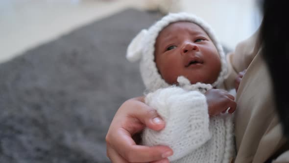 Close up newborn baby is held by his mother and he look around then look to mother face alt
