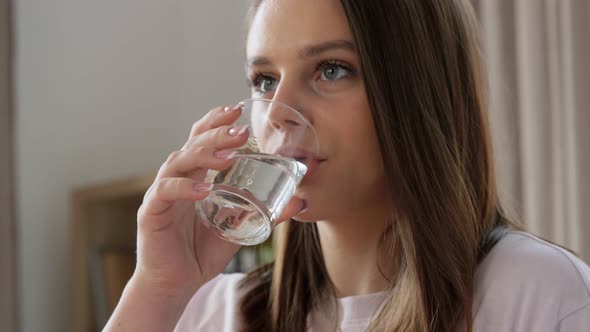 Smiling Girl with Glass Drinking Water at Home