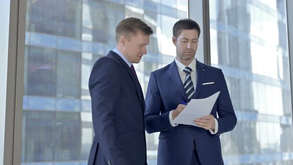 Two Middle Aged Businessmen Discussing the Documents and Shaking Hands in Office alt