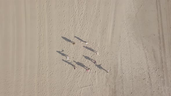Aerial view of children teenagers play ball on the sandy beach by the sea, summer vacation. Zoom out alt