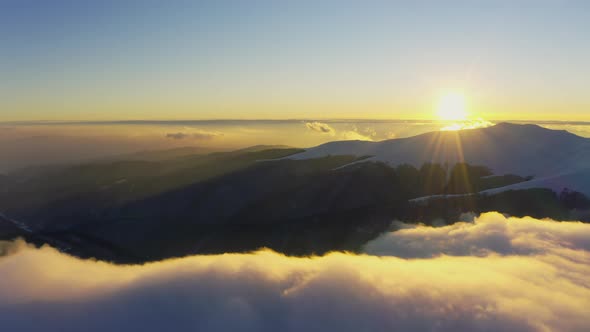 Cloud Waves Gently and Slowly Flow Over the Tops of Snowcapped Mountains Covered with Spruce Forests alt