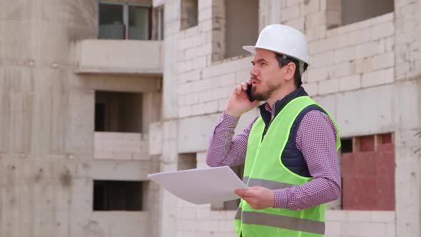 Young Engineer Working on Building Site  and Giving tasks over the Phone