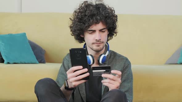 Young Man Shopping Online with Credit Card Using Smart Phone at Home alt