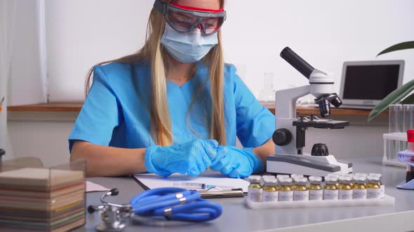 Woman Laboratory Worker Fills in the Syringe with Experimental Drug From Vial alt