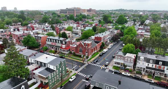 Aerial angled view of town street. Rainy, wet spring day over city. Single family homes lining city alt
