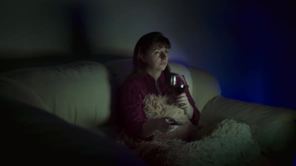 Woman with a Glass of Wine Sits at Home on the Sofa in the Evening and Watches Tv Deep Feelings alt