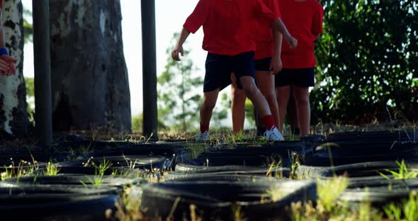 Kids running over tyres during obstacle course training alt