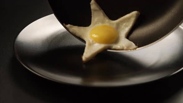 Taking out of a fried eggs in a form of a star from the pan to the dish