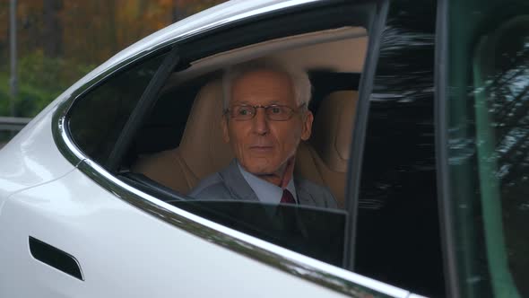 a Man Rides with an Open Window Sitting in the Back Seat of a Car