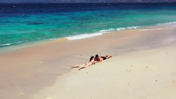 Man and woman sunbathe on beautiful lagoon beach trip by turquoise lagoon with white sandy backgroun alt