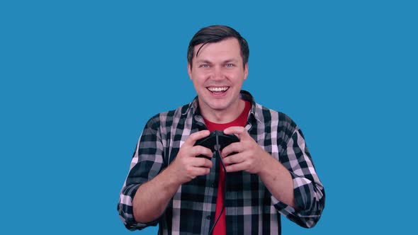 A man gamer plays video games with a joystick with a joyful expression on his face