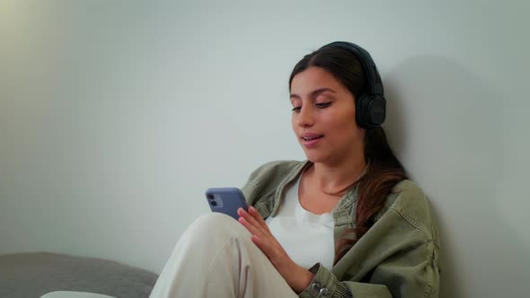 Young Girl Resting at Home Listening to Music on Headphones and Singing While Dancing While Sitting