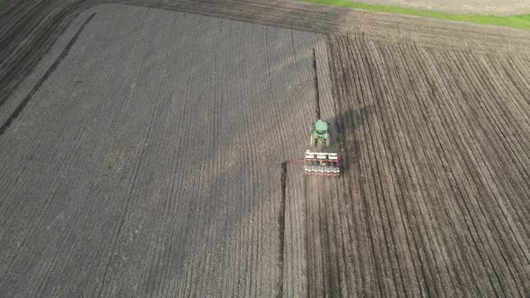 Aerial view of agriculture field being tilled for planting. Trees casting shadows across the field.