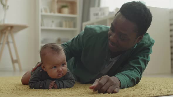 Infant and Her Father Lying on Carpet at Home alt