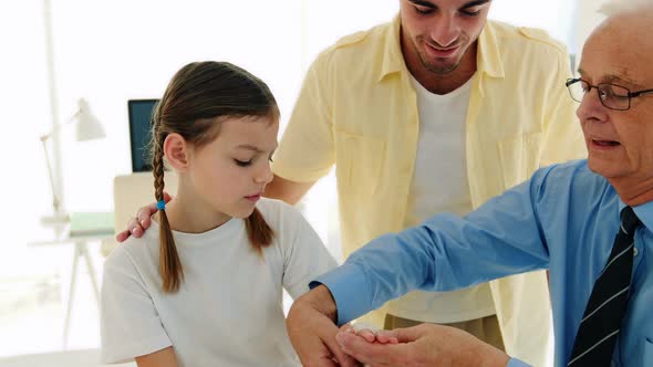 Doctor applying bandage to girls hand alt