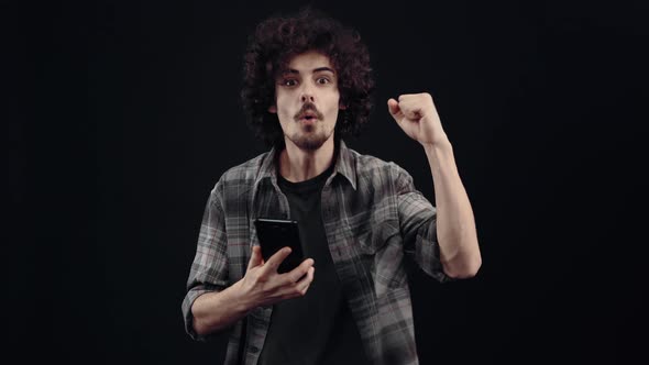 The Charismatic Young Man Focused Looks on the Phone After Which He Receives a Message and He alt