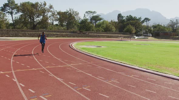 Disabled mixed race man with prosthetic legs running on race track alt