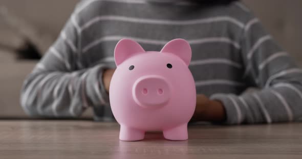 Hand girl putting coins into piggy bank alt