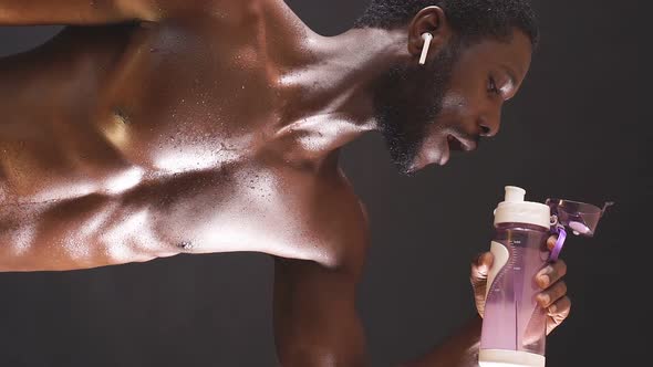 A Muscular Shirtless Man Poses Against an Isolated Dark Background alt