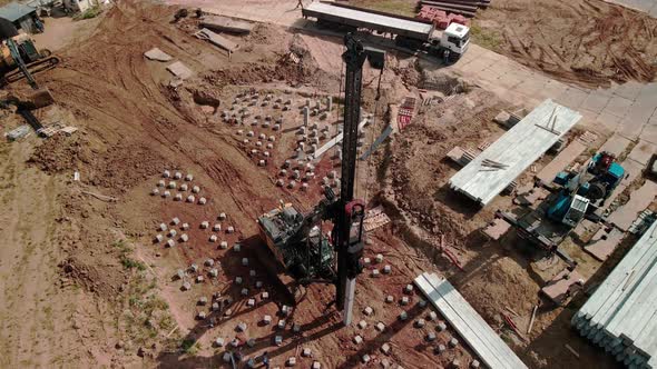A Large Vertical Piledriving Crane Hammers Reinforced Concrete Piles Into the Ground at a alt