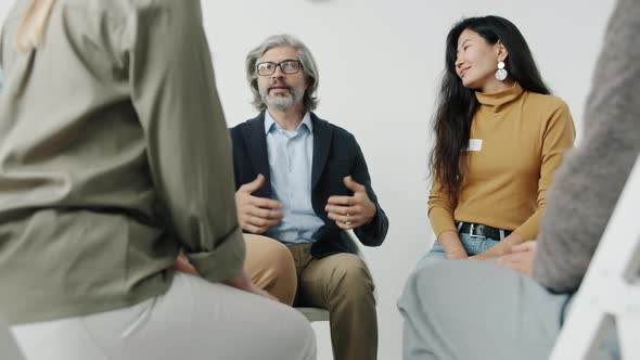 Portrait of People Holding Hands Talking and Smiling During Group Therapy Meeting Indoors alt
