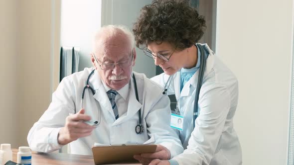 Expert examining medical history sheet with young doctor