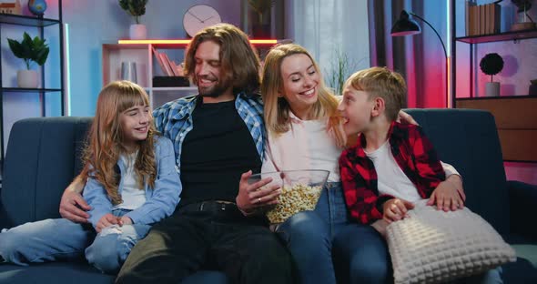 Family Sitting Together on the Comfortable Couch and Looking Into Camera alt