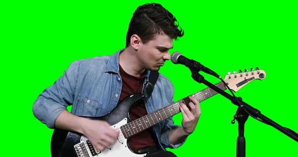 Male musician singing while playing guitar alt