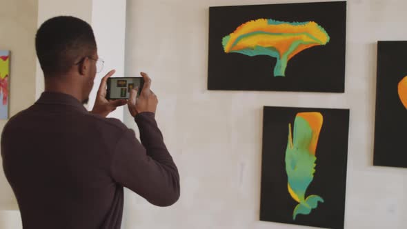 Afro-American Man Photographing Artwork in Gallery alt