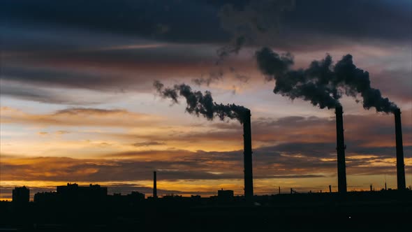 Smoke From High Industrial Pipes at Sunrise Against the Backdrop of the Urban Environment alt