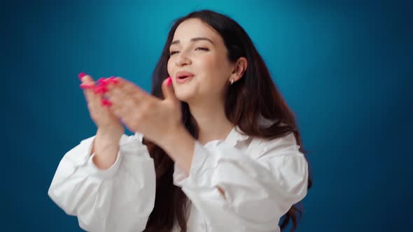 Young Brunette Woman Blowing Kisses Against Blue Background