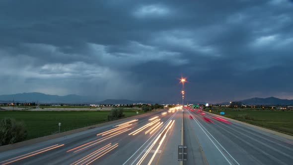 Time lapse of traffic driving on highway as storm and lightning passes alt