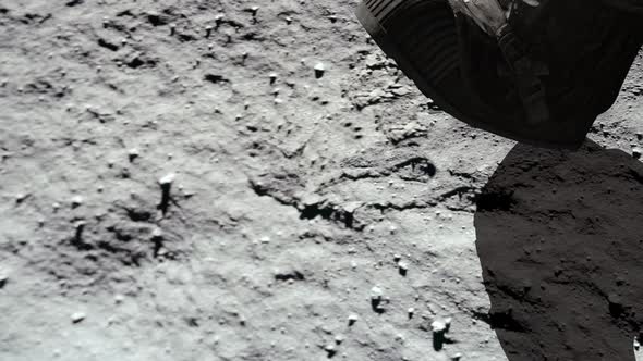 Lunar astronaut walking on the moon's surface and leaves a footprint in the lunar soil