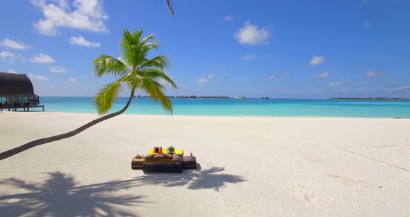 Aerial view of a couple lounging on a beach at a tropical island resort hotel. alt