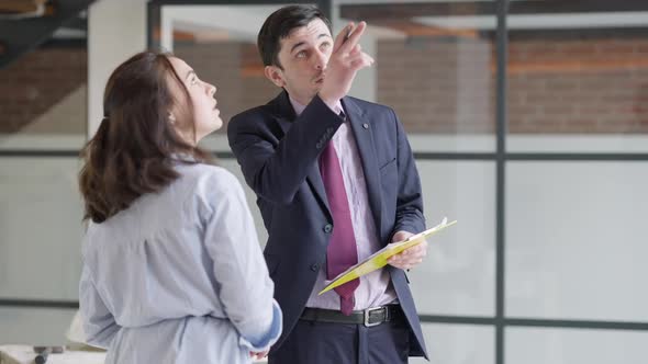 Concentrated Caucasian Man and Woman Comparing Plan and Renovation of Apartment alt